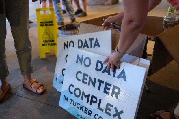 Volunteers hand out yard signs against a data center complex in Canaan Valley on June 30, 2025, after a public meeting organised by the West Virginia Departement of Environmental Protection regarding the air quality permit application for a gas-fired power plant near Davis, West Virginia. The mayor and some residents of Davis, a town about a three-hour drive from Washington and home to 600 people, are fighting against construction of the mysterious project on the outskirts of Davis, designed to power a vast data center. This fight in the woods of rural West Virginia is the latest example of the war between the US tech sector -- and its rapidly rising need for energy to power the AI boom -- and the communities it affects. (Photo by Ulysse BELLIER / AFP) (Photo by ULYSSE BELLIER/AFP via Getty Images)